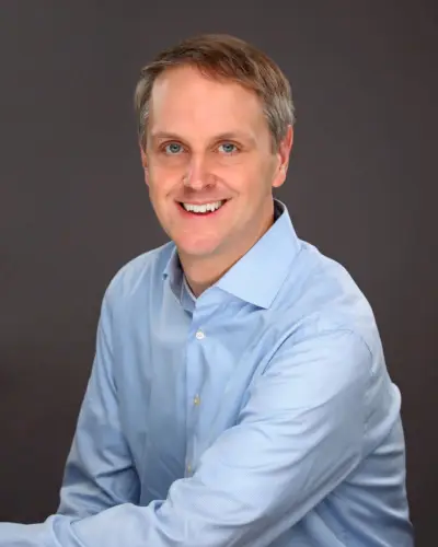 Eric Young sorride indossando una maglietta blu.