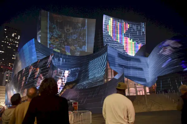 Le persone guardano il grande edificio in acciaio con proiezioni colorate su di esso