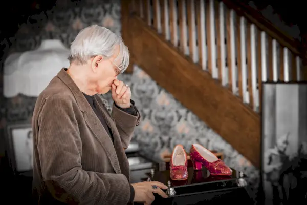 Mies ruskeassa vakosamettitakissa katsoo punaisia ​​tossuja