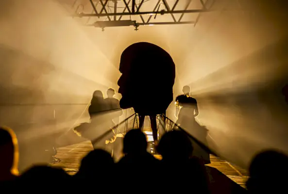 Esiintyjien varjot Leninin jättiläispään siluetin edessä