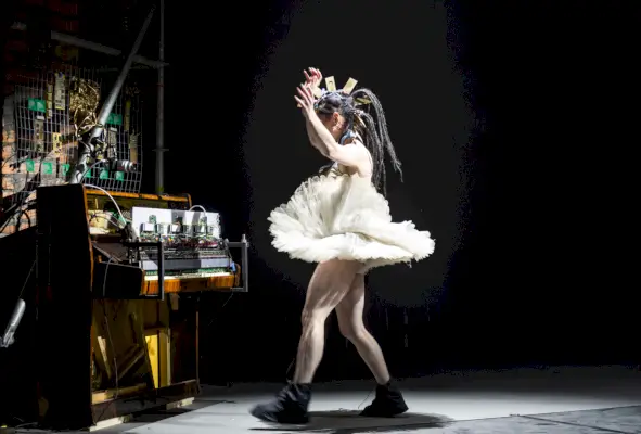 Nainen tutuissa ja taistelusaappaat seisoo elektronisen instrumentin sisäelinten edessä