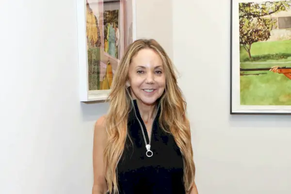 Nainen, jolla on pitkät vaaleat hiukset, seisoo taidegalleriassa