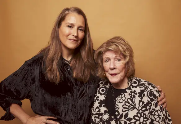 Äiti ja tytär kaksikko poseeraa oranssin taustan edessä