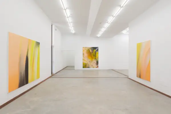 Valokuva valkoisesta kuutiohuoneesta keltaisilla maalauksilla