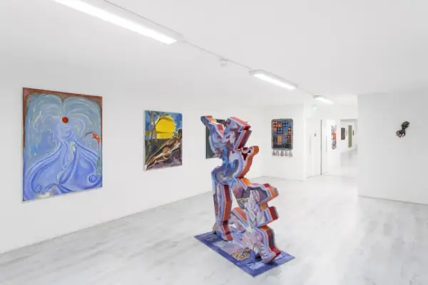 Ett skarpt vitt konstgalleri med skulpturer och målningar