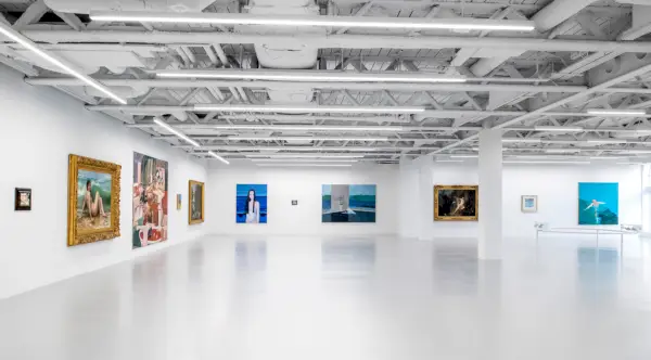 Målningar på väggen i ett konstgalleri med synliga tak