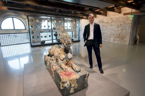 L'uomo di mezza età posa accanto alla scultura in pietra della sfinge sul piedistallo nella sala espositiva.