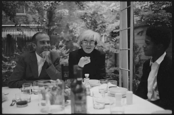 Mustavalkoinen valokuva kolmesta ihmisestä istumassa ulkopöydän ääressä