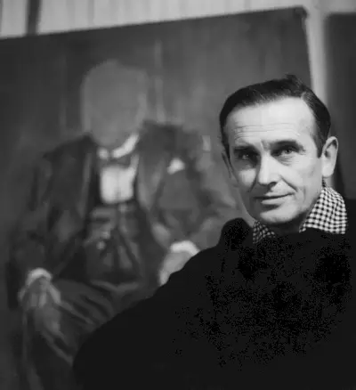 Foto in bianco e nero di un uomo seduto davanti a un ritratto senza volto