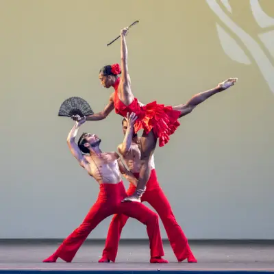 Un trio di ballerini si esibisce sul palco con un ventaglio pieghevole