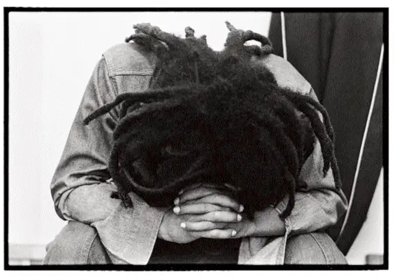 Mies, jolla on rastatukka, nojautuu alas kädet ristissä mustavalkoiseen valokuvaan