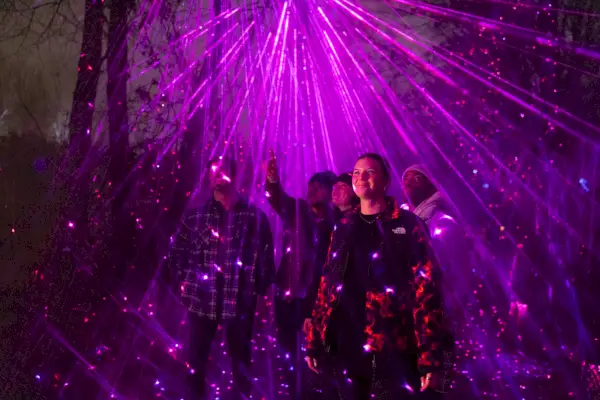 Ihmiset seisovat violetin laservalonäytön alla