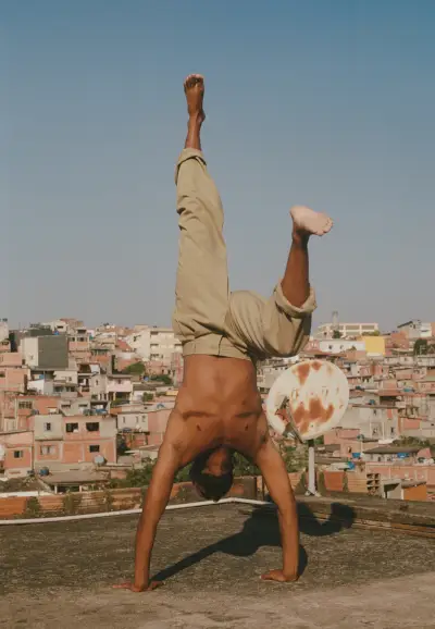Zdjęcie przedstawiające osobę z bliznami na mięśniach piersiowych w stanie na rękach, za nią widoczne Sao Paulo.