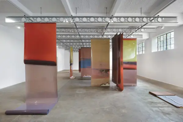 Grafika wykonana z dużych arkuszy kolorowej tkaniny zwisających z sufitu