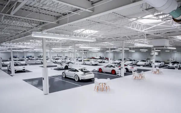 Rzędy białych samochodów sportowych Porsche przedstawionych w dużym magazynie