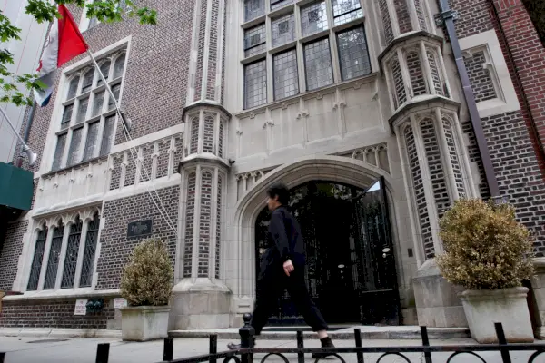 Un uomo cammina accanto ad un elegante edificio in mattoni con un ampio ingresso in marmo