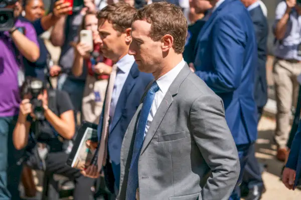 En sidoprofil av Mark Zuckerberg med en stor skara fotografer i bakgrunden.