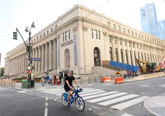 Henkilö ajaa polkupyörällä postirakennuksen ulkopuolella New Yorkissa.