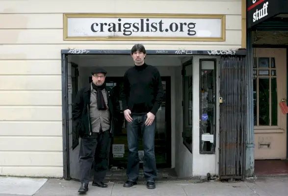 Due uomini stanno davanti a un edificio squallido con