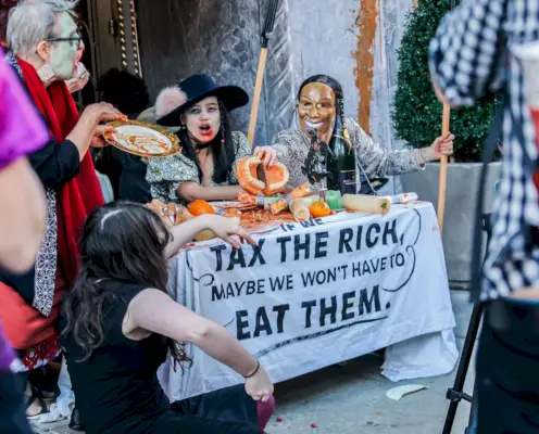 Mielenosoittajat polvistuvat pöydän takana, jossa on ruokaa ja kyltti