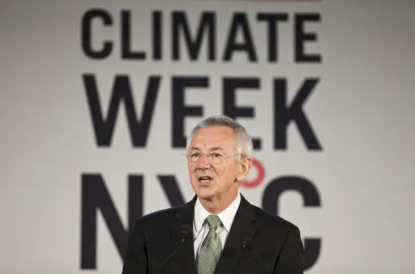 Vanhempi valkoinen mies harmaat hiukset ja lasit yllään musta puku.