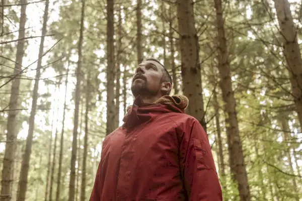 Un uomo con un cappotto invernale si trova in una foresta