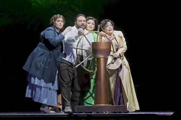 En skara människor i gammaldags klänning kryper runt ratten på ett fartyg