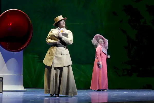 Två operaartister i gammaldags klänningar står på en scen