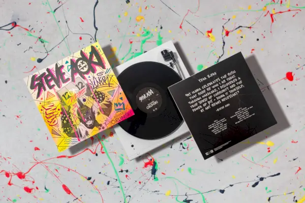 Uno scatto lifestyle con la copertina colorata di un disco in vinile, un disco e il retro nero della copertina.