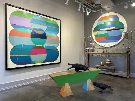 Kulmakuva taidegalleriasta, jossa on kirkkaita maalauksia seinällä