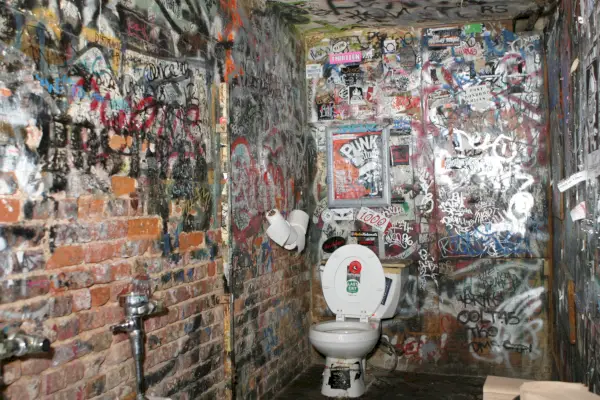 Likainen kylpyhuone, jota ympäröivät graffitit peittävät seinät