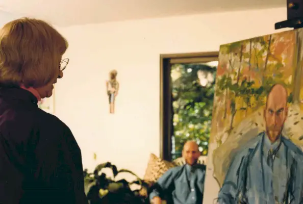 Mies istuu ikkunan vieressä, kun nainen maalaa hänen muotokuvaansa