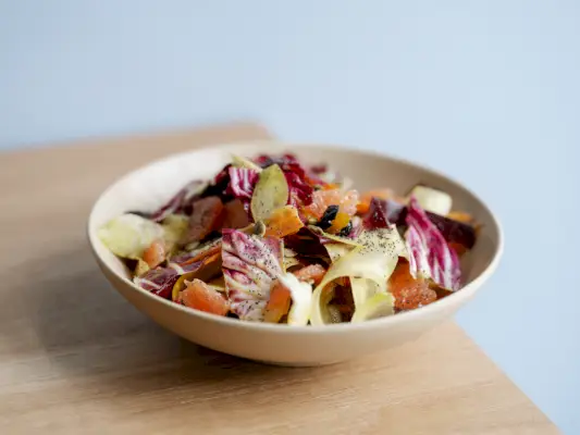 ruokaa valkoisessa kulhossa puupöydällä