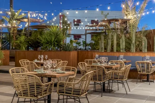 Un patio esterno con verde, tavoli, divani e sedie.