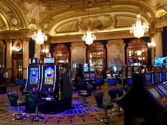 Casino de Monte-Carlon peliautomaatit ja yksityiskohtainen katto maalauksilla ja kultaisilla yksityiskohdilla.
