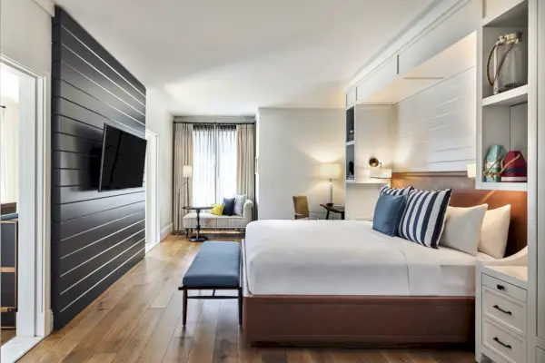 Gästrum på Lido House med en säng till höger, TV till vänster och fönster i bakgrunden.