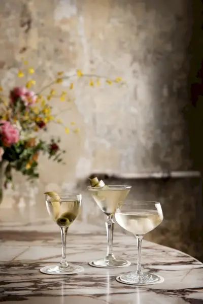 Kolme erikokoista suolakurkkumartiinia marmoripöydällä ja taustalla kukkia.