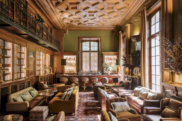 bar biblioteczny z książkami oprawionymi w skórę pod kasetonowym sufitem, ze spiralnymi schodami i pluszowymi siedzeniami.