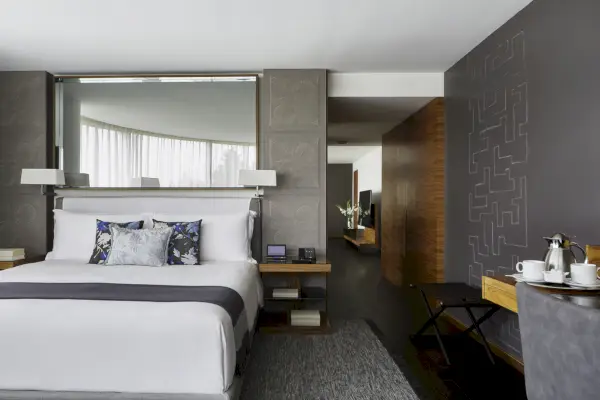 Hotellisviitti, jossa on valkoinen sänky ja harmaa seinä.