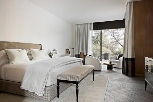 Valkoinen hotellihuone, jossa on lasiliukuovet, jotka johtavat omalle patiolle.