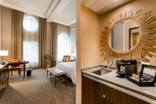 Gæsteværelse på Hotel Birks i Montreal med et vådt barområde og en seng og et vindue i baggrunden.