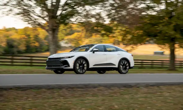 valkoinen toyota-kruunuauto, joka ajaa tiellä