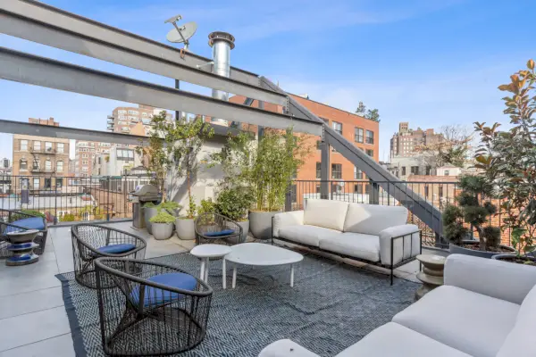 Kattoterassi, jossa on valkoiset lounge-huonekalut ja näkymät NYC:n horisonttiin.