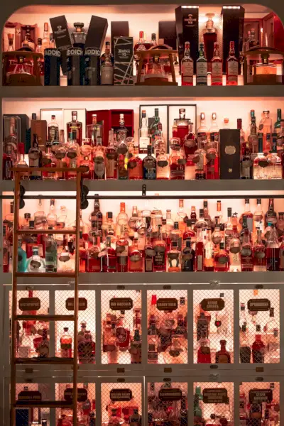 Un gigantesco mobile retroilluminato di rosso pieno di bottiglie di whisky.