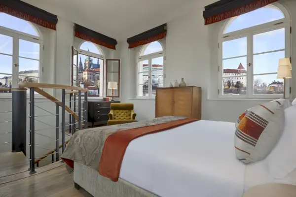 Pokój hotelowy z białym łóżkiem i wieloma oknami