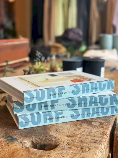 tre staplade böcker som säger surf shack i en butik