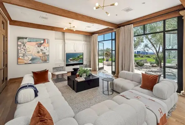 Una sala d'estar amb sofàs blancs de grans dimensions dóna a un paisatge verd exuberant.