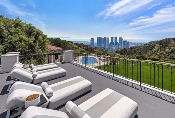 Un balcó amb tres gandules té vistes a una piscina i a l'horitzó de Los Angeles.