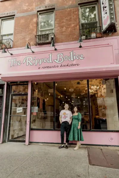 due persone in piedi davanti a una vetrina rosa a Brooklyn che dice il corpetto strappato