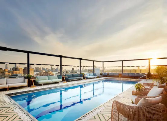 kattouima-allas auringonlaskun aikaan näköalalla NYC:hen